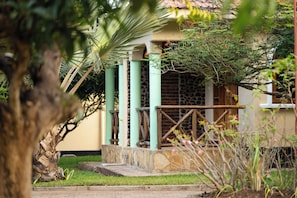 Un edificio con pared de piedra, puerta de madera y portón metálico.
