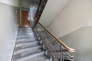 Eine Treppe mit Metallgeländern und Holzhandläufen, die zu einer Tür oben führt.