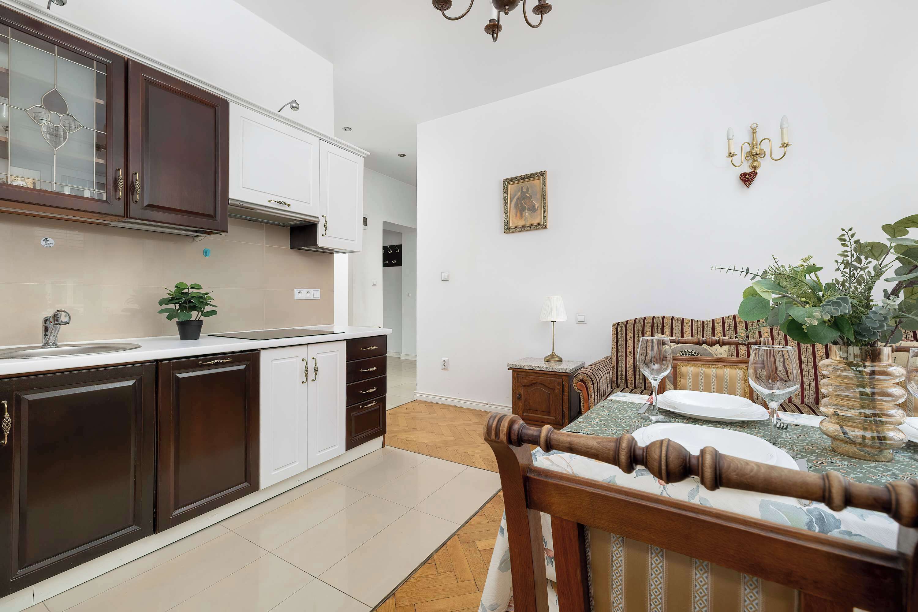 A modern kitchen with dark cabinets, a white countertop, and a dining area with a table set for two.