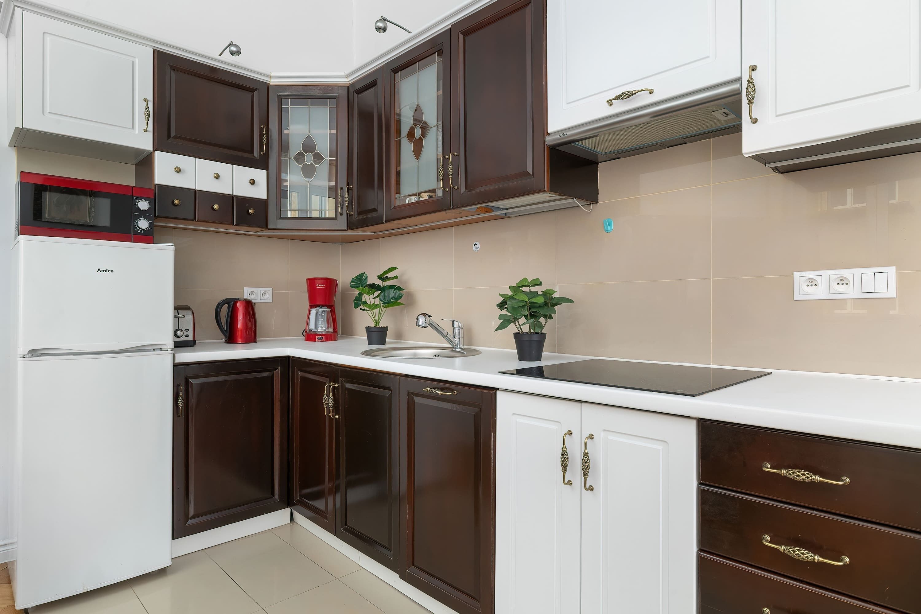 A modern kitchen with white and dark brown cabinetry, a built-in microwave, a coffee maker, and a sink.