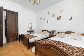 A hotel room with two wooden beds, a chandelier, and several framed pictures on the wall. - Apartment with Soul | Bedroom (Kraków)