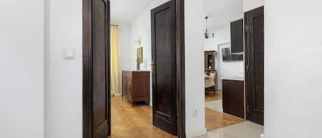 Un pasillo con una puerta de madera que da a un comedor con una mesa y sillas.