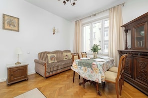 A furnished living room with a sofa, dining table, and a cabinet. - Apartment with Soul | Bedroom (Kraków)