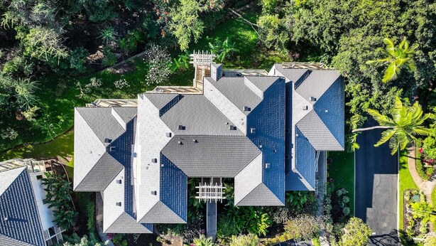 A modern building with a unique geometric roof design, surrounded by lush greenery and a parking area. - Wailea Blue Golf Course Condo-Walk to Shops, Beach (Wailea-Makena)