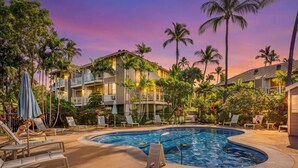 A swimming pool with lounge chairs and palm trees, surrounded by multi-story buildings. - Wailea Blue Golf Course Condo-Walk to Shops, Beach (Wailea-Makena)