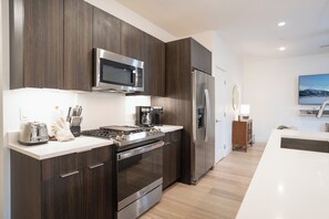 A modern kitchen with dark wood cabinets, stainless steel appliances, a built-in microwave, and a refrigerator. - River West Rivers And Roads Condo: Mountain Views, Shared Hot Tubs (Slverthorne)
