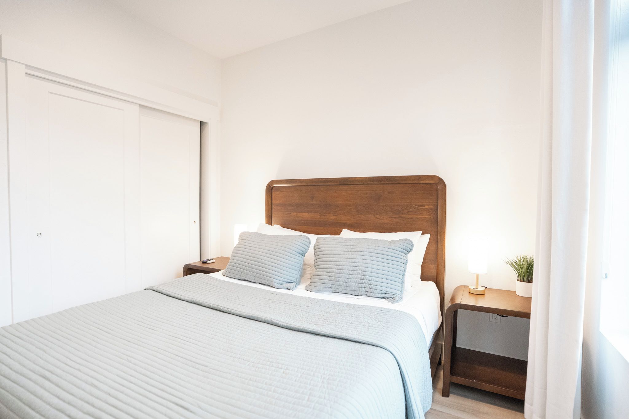 A bedroom with a bed, two bedside tables, a nightstand, and a window.