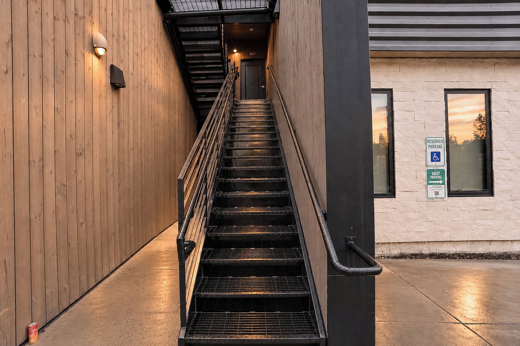 Een trap die leidt naar een deur met het nummer 621, met een bord waarop reserveringsplaatsen en gastenparkeerplaatsen worden aangegeven.