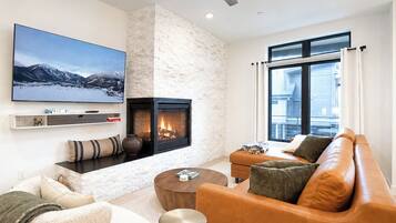 Een moderne woonkamer met een open haard, een grote flatscreen televisie en een bank.