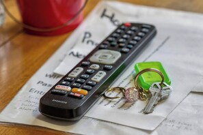 A remote control with keys and a green keychain on a piece of paper.