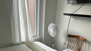 A neatly made bed with a green throw, a standing fan, a wooden chair, and a TV mounted on the wall. - Comfortable & Cozy Private Room in a Shared House (Room1) (Toronto)