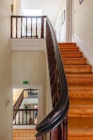 Una escalera de madera con barandilla negra que sube a un piso superior.