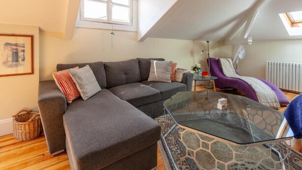 A modern living room with a sectional sofa, a glass coffee table, and a purple chair. - S.K.Y. Accommodations Family studios  (Coimbra)
