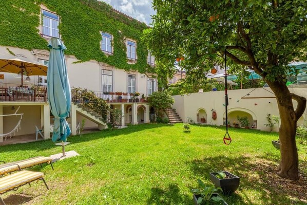 Un patio con un árbol, una hamaca colgante y una zona de estar techada.