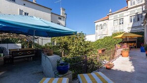 A courtyard with outdoor seating, a blue umbrella, and potted plants. - S.K.Y. Accommodations Family studios  (Coimbra)
