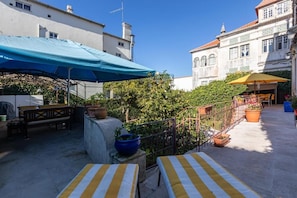 A courtyard with outdoor seating, a blue umbrella, and potted plants. - S.K.Y. Accommodations Family studios  (Coimbra)
