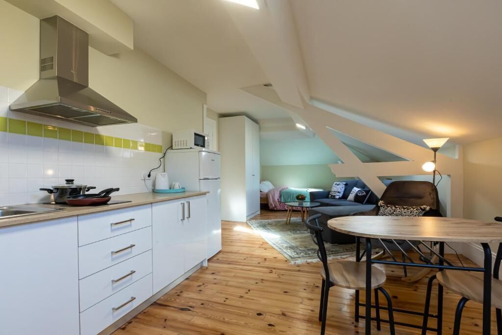 Una cocina moderna con gabinetes blancos, extractor de acero inoxidable y microondas. Hay un comedor con una mesa redonda y sillas.