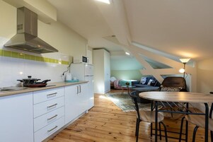 Una cocina moderna con gabinetes blancos, extractor de acero inoxidable y microondas. Hay un comedor con una mesa redonda y sillas.