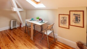 A dining area with a table and chairs, a radiator, and framed pictures on the wall. - S.K.Y. Accommodations Family studios  (Coimbra)