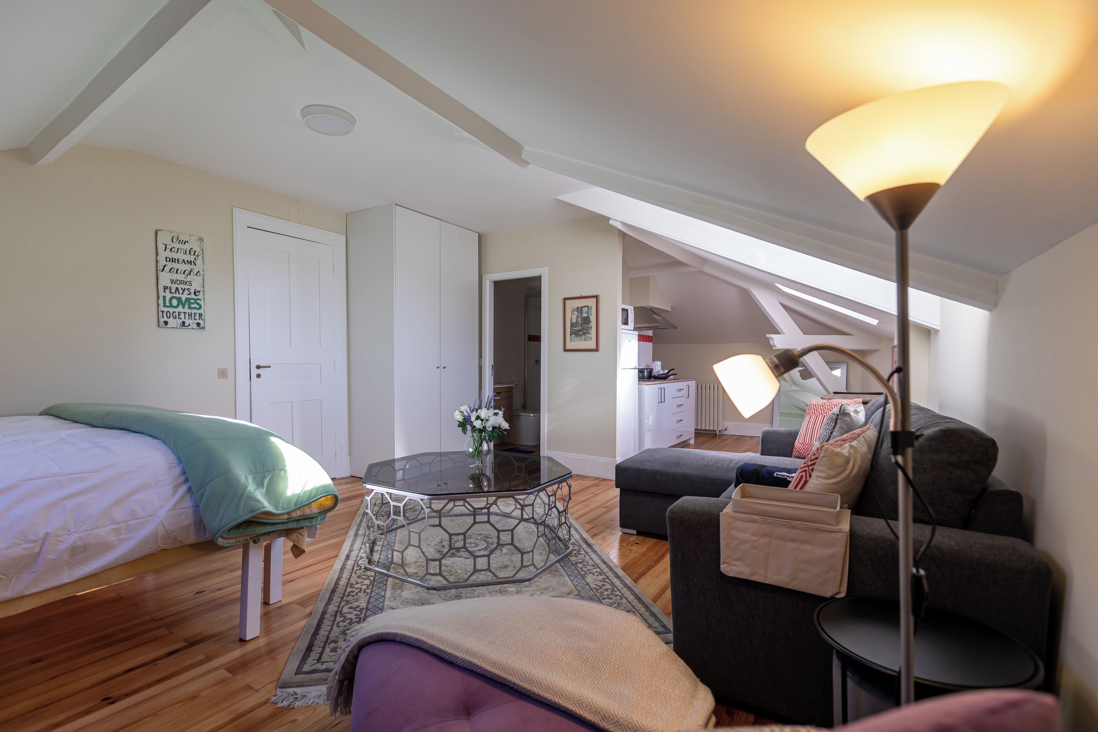 Ein gemütliches Zimmer mit einem Bett, einem Sofa, einem Glastisch und einer Lampe.