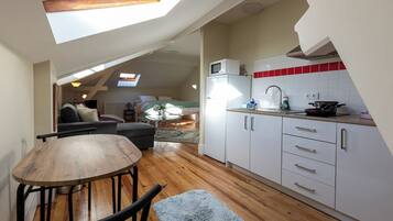 A loft-style apartment with a dining area, kitchenette, and a living space with a sofa and a coffee table.