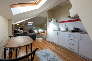 A loft-style apartment with a dining area, kitchenette, and a living space with a sofa and a coffee table.