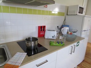 A kitchen with a microwave, toaster, kettle, and a sink.
