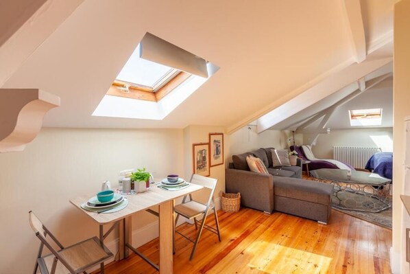 A cozy loft apartment with a dining area, a sofa, and a small table.