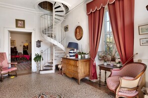 A room with a spiral staircase, a wooden cabinet, a patterned chair, and a dining area with a red tablecloth. - Bed and Breakfast 'Chambre Esclarmonde' with Shared Pool, Shared Garden and Wi-Fi (Carcassonne)