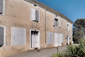 Un bâtiment doté de nombreuses fenêtres et portes, d’un toit recouvert de tuiles et d’un sol en gravier.