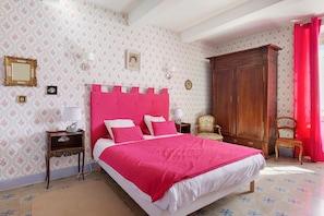 Une chambre à coucher avec un grand lit, une armoire en bois et un papier peint à motifs floraux.