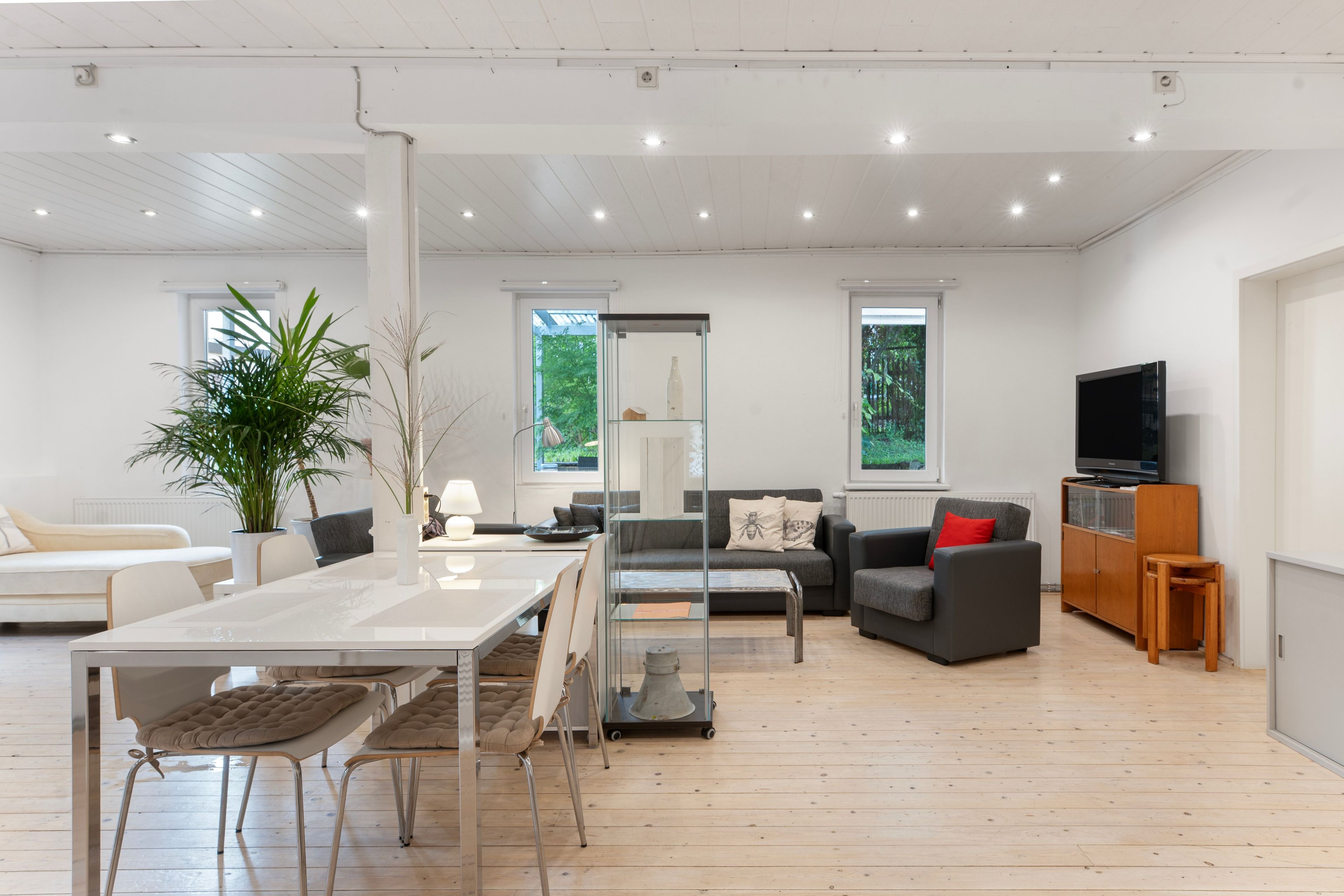 Un salon moderne comprenant un coin repas, un ensemble de canapés, un téléviseur et une grande fenêtre.