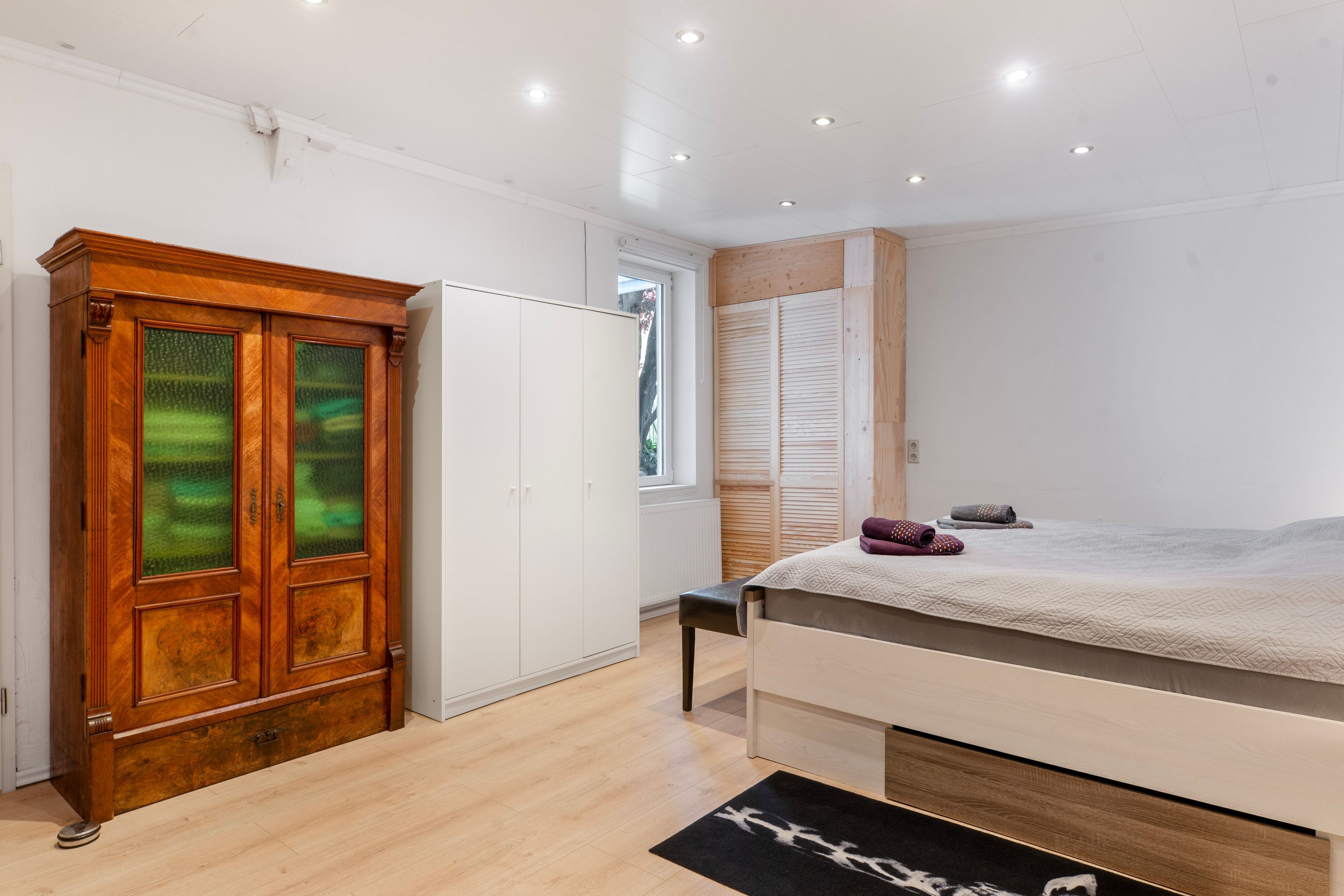 Ein Schlafzimmer mit Bett, Kleiderschrank und Fenster.