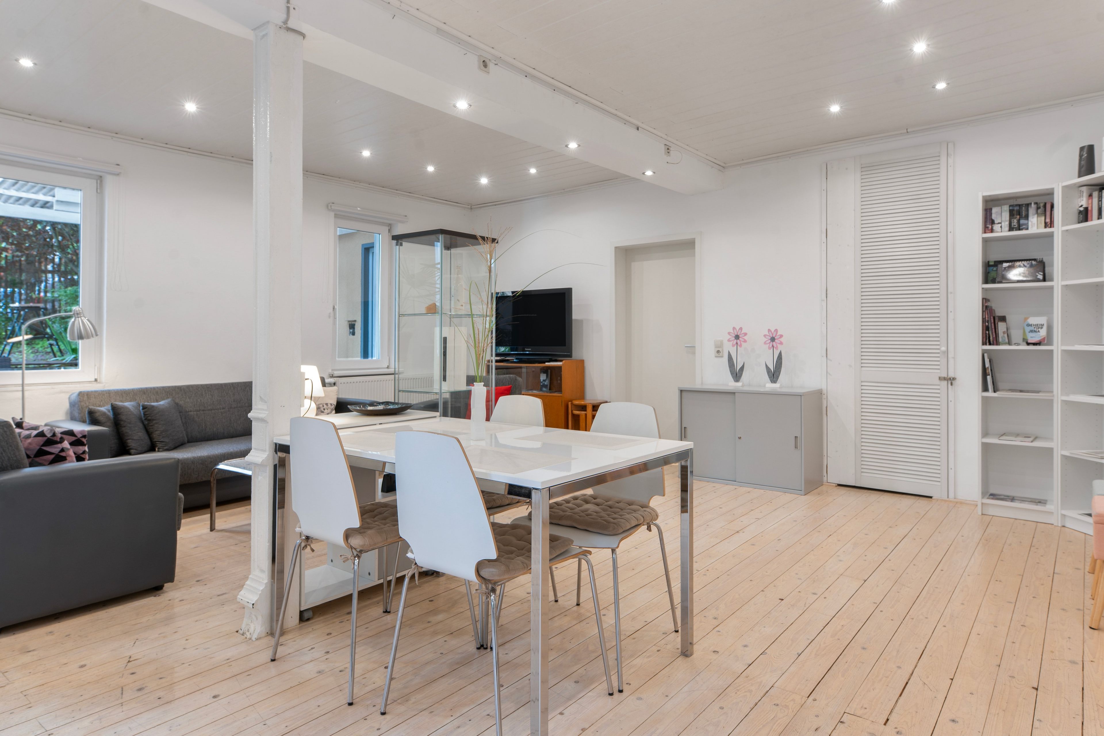 Una sala de estar moderna con comedor, televisor de pantalla plana y estantería.