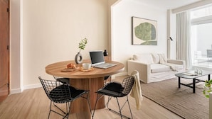 Un salon moderne avec une table ronde en bois, des chaises à armature métallique noire, un canapé blanc et une table basse.