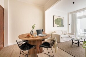 Uma sala de estar moderna com uma mesa redonda de madeira, cadeiras de arame preto, um sofá branco e uma mesa de centro.