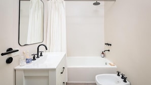 Une salle de bain moderne avec un lavabo blanc, un miroir, une douche et des toilettes.