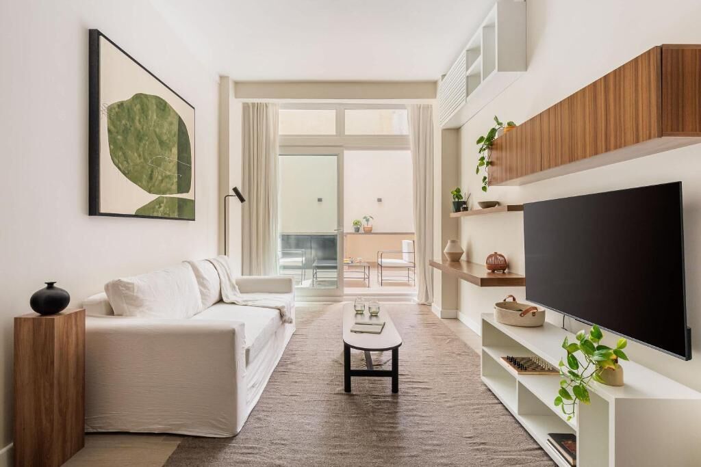 A modern living room with a sofa, coffee table, TV, and a large window.