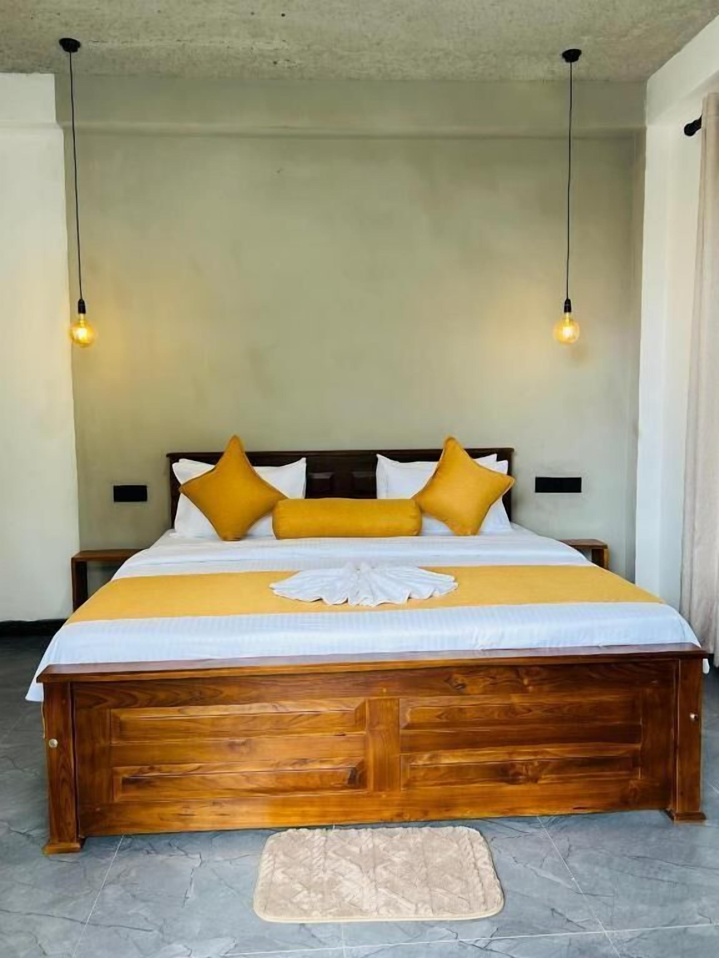 A bed with a wooden frame, a yellow bedspread, and two light bulbs hanging above.