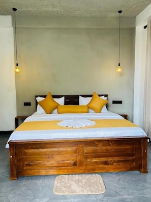 Una cama con estructura de madera, una colcha amarilla y dos bombillas colgando encima.