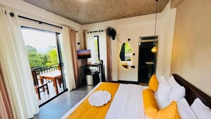 A hotel room with a large bed, a balcony, a kitchenette, and a view of greenery. - Leafveil Ella (Ella)