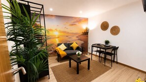 A living room with a sofa, coffee table, and a dining table set for two. - 77 Lisbon Design Studio near Airport (Sintra)