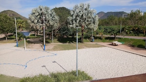 Una zona de playa arenosa con palmeras y una montaña al fondo.