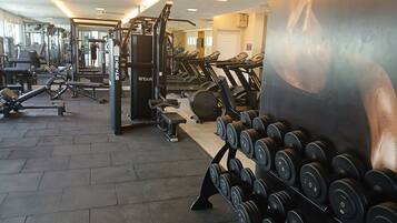 A gym with various exercise equipment, including treadmills, dumbbells, and weight machines.