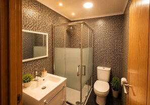 Un bagno con cabina doccia in vetro, un water e un lavabo con specchio sopra.