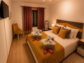 Una camera d'albergo con un letto, una sedia, un comodino, una lampada e un televisore.