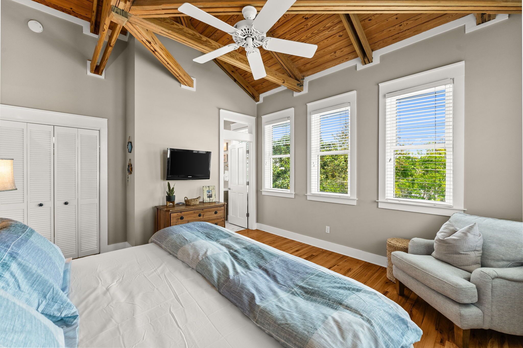 Ein Schlafzimmer mit Bett, Kommode, Fernseher und Deckenventilator.