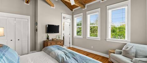 A bedroom with a bed, a dresser, a TV, and a ceiling fan.