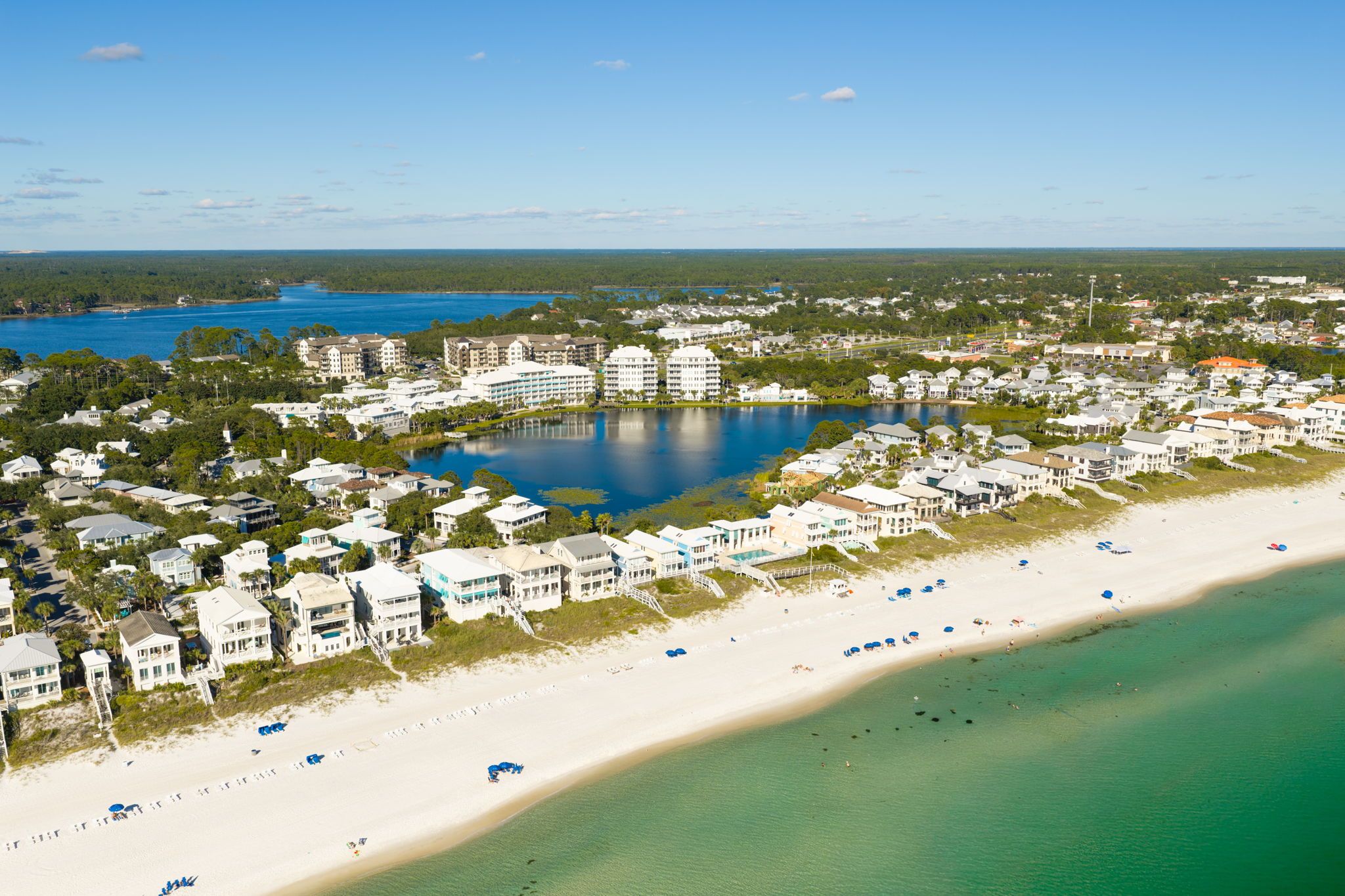 A coastal resort with beachfront properties, a central lake, and a sandy beach.