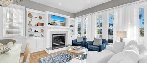 A modern living room with a fireplace, a television, and a view of the outdoors.